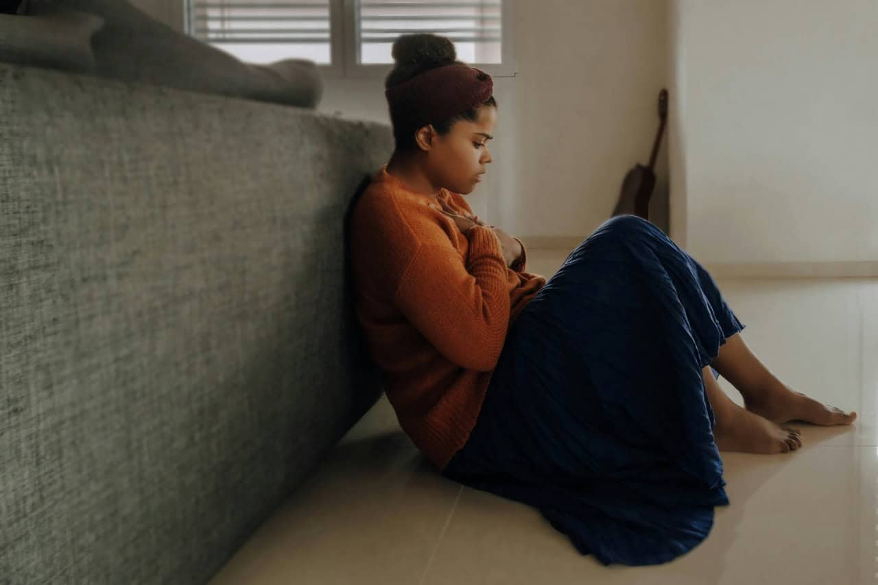 Supportive woman sitting alone on the floor, seeking comfort and emotional healing.